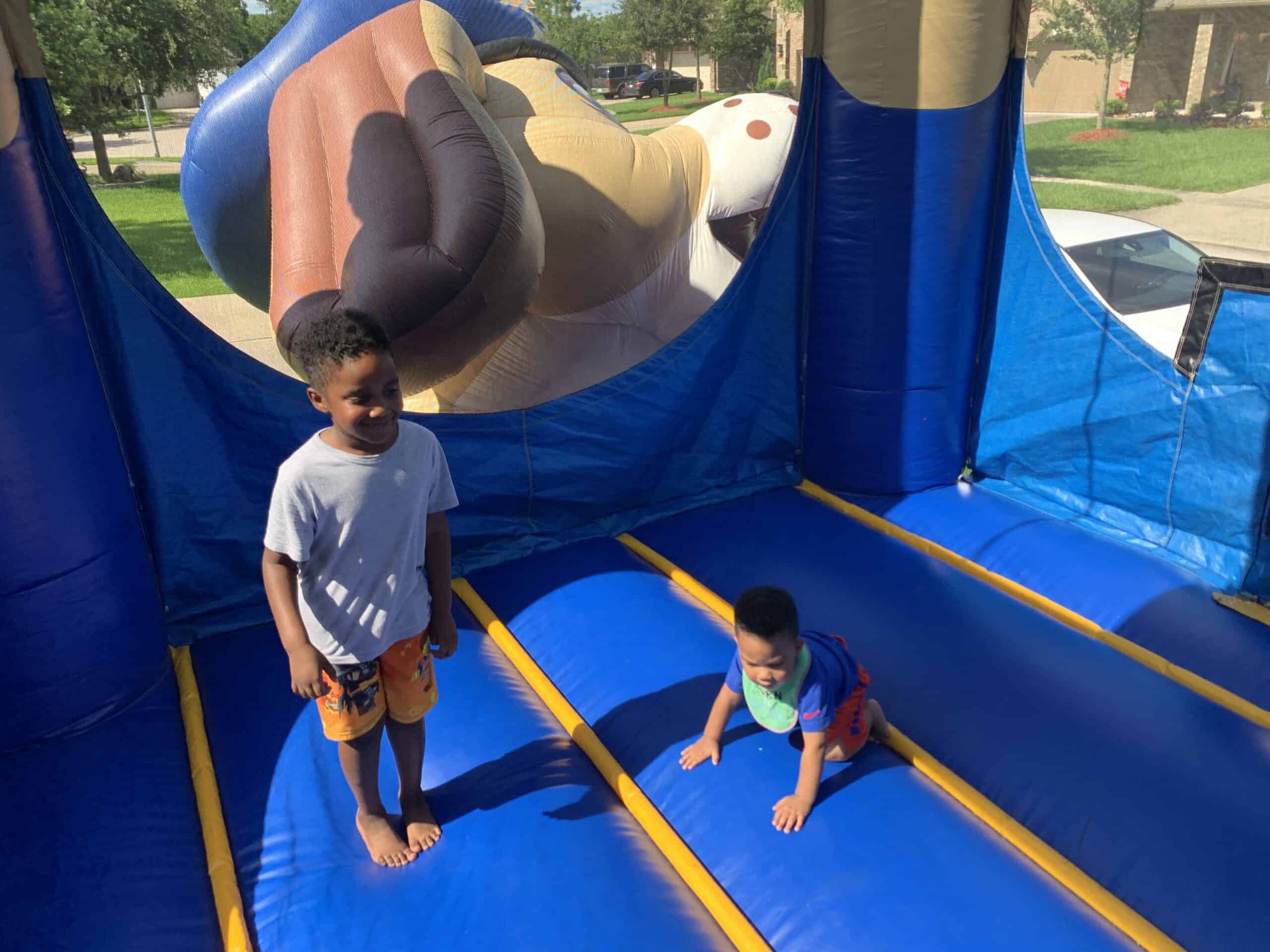 Children Playing inside Bounce Rental Two young boys standing and playing inside a blue inflatable bounce unit.