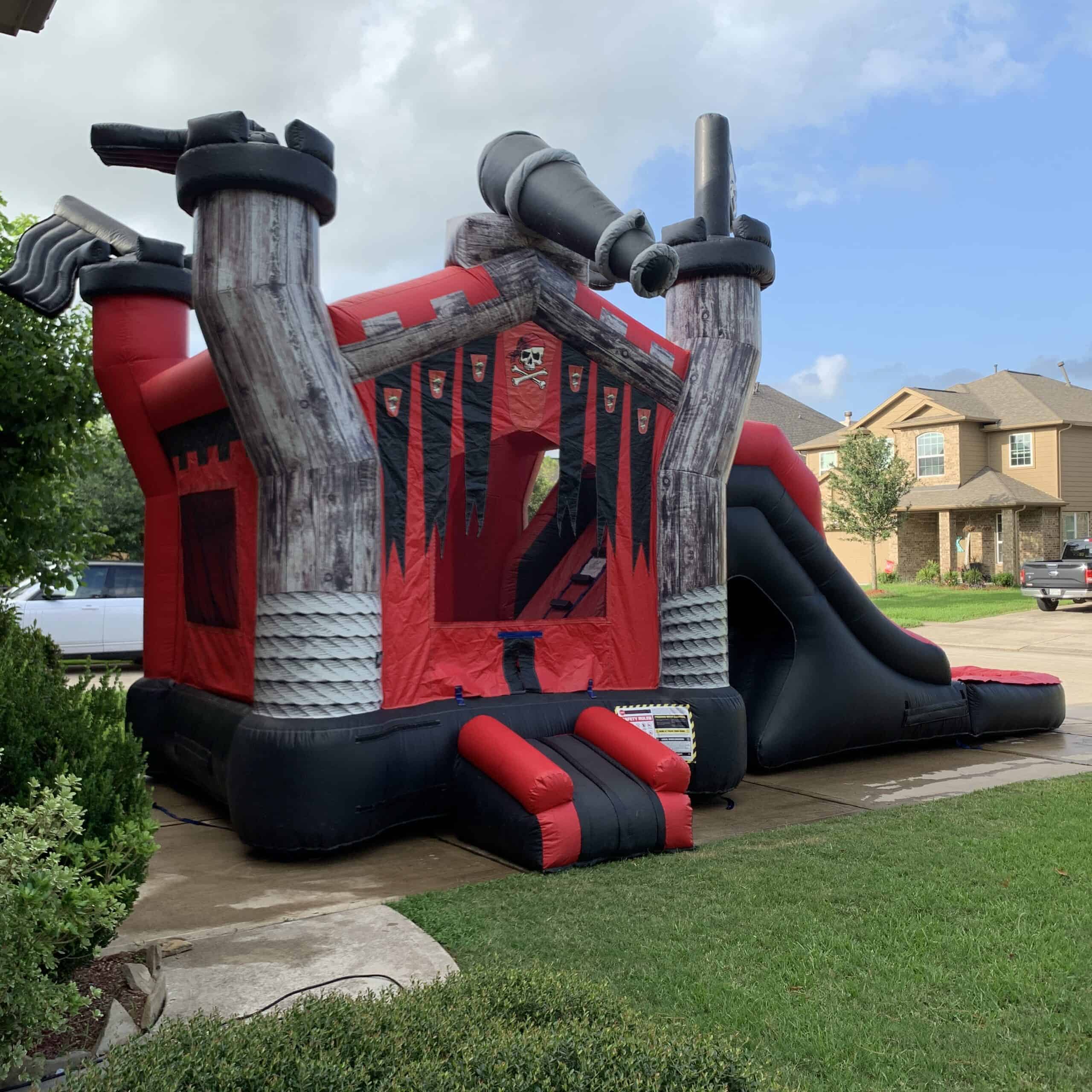 Pirate ship inflatable bounce house and slide combination set up on a driveway.