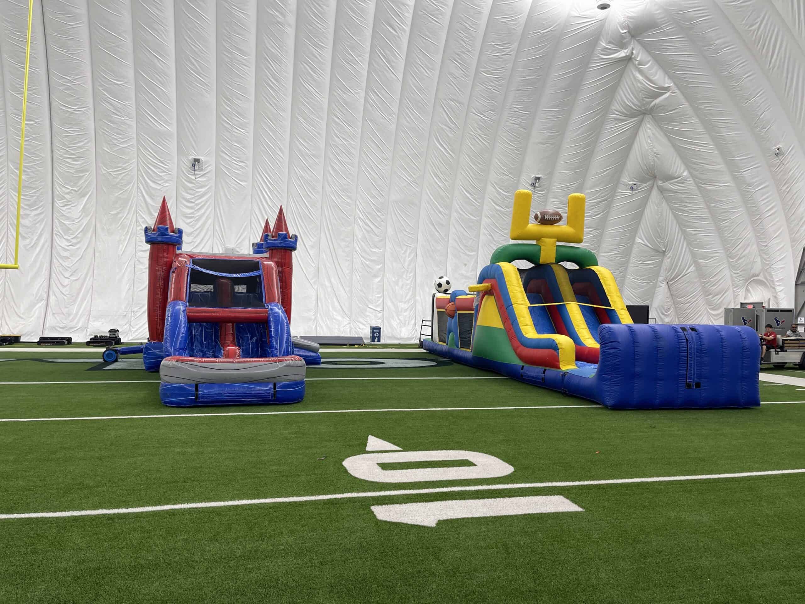 Indoor Inflatable Rentals on Turf Field Red and blue inflatable bounce house and sports combo set up on an indoor turf field