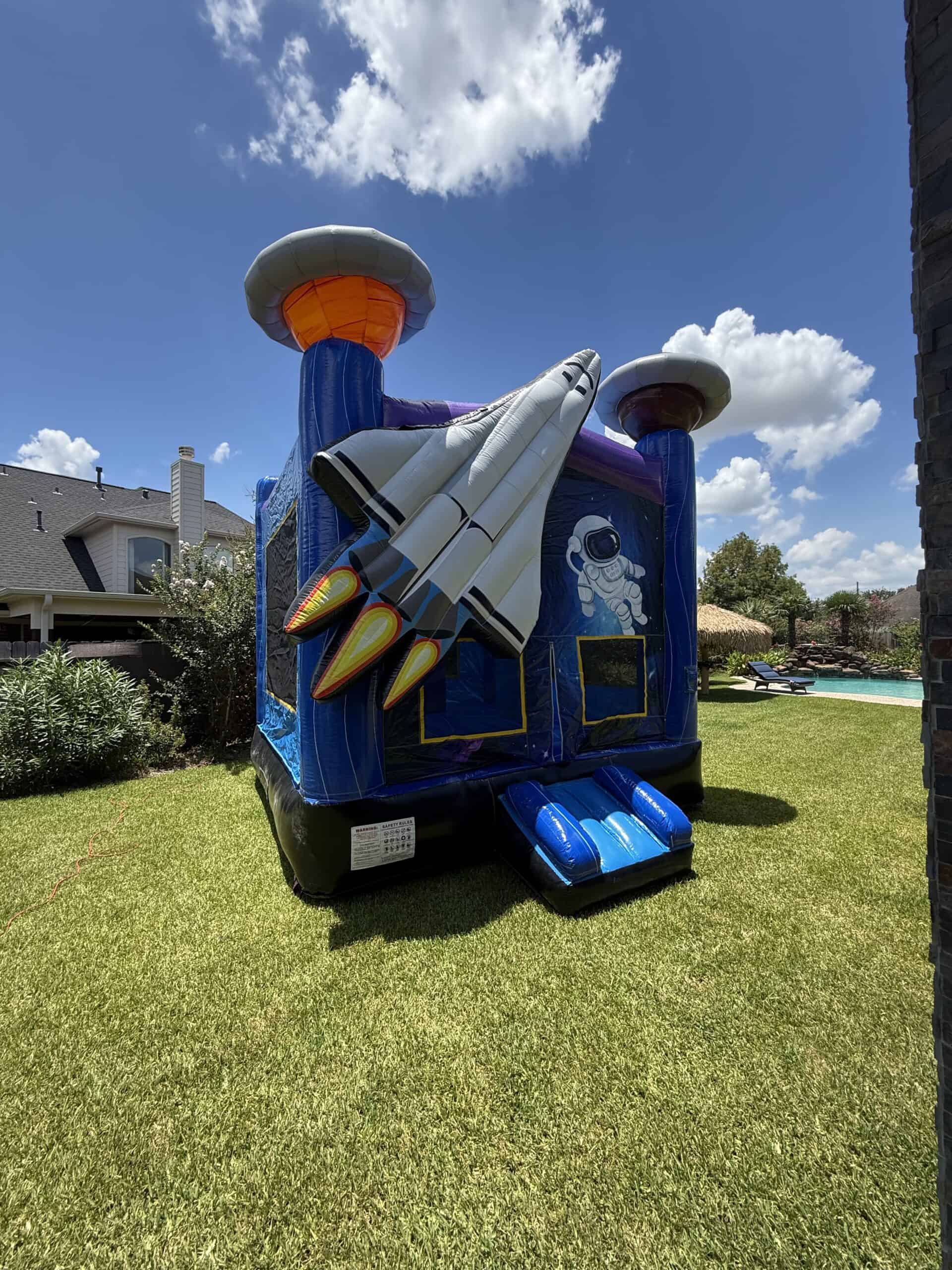 Colorful space-themed inflatable bounce house with rocket and planets for kids.