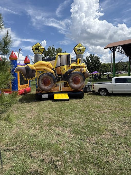 Yellow excavator-themed bounce house at Party Kids America event.