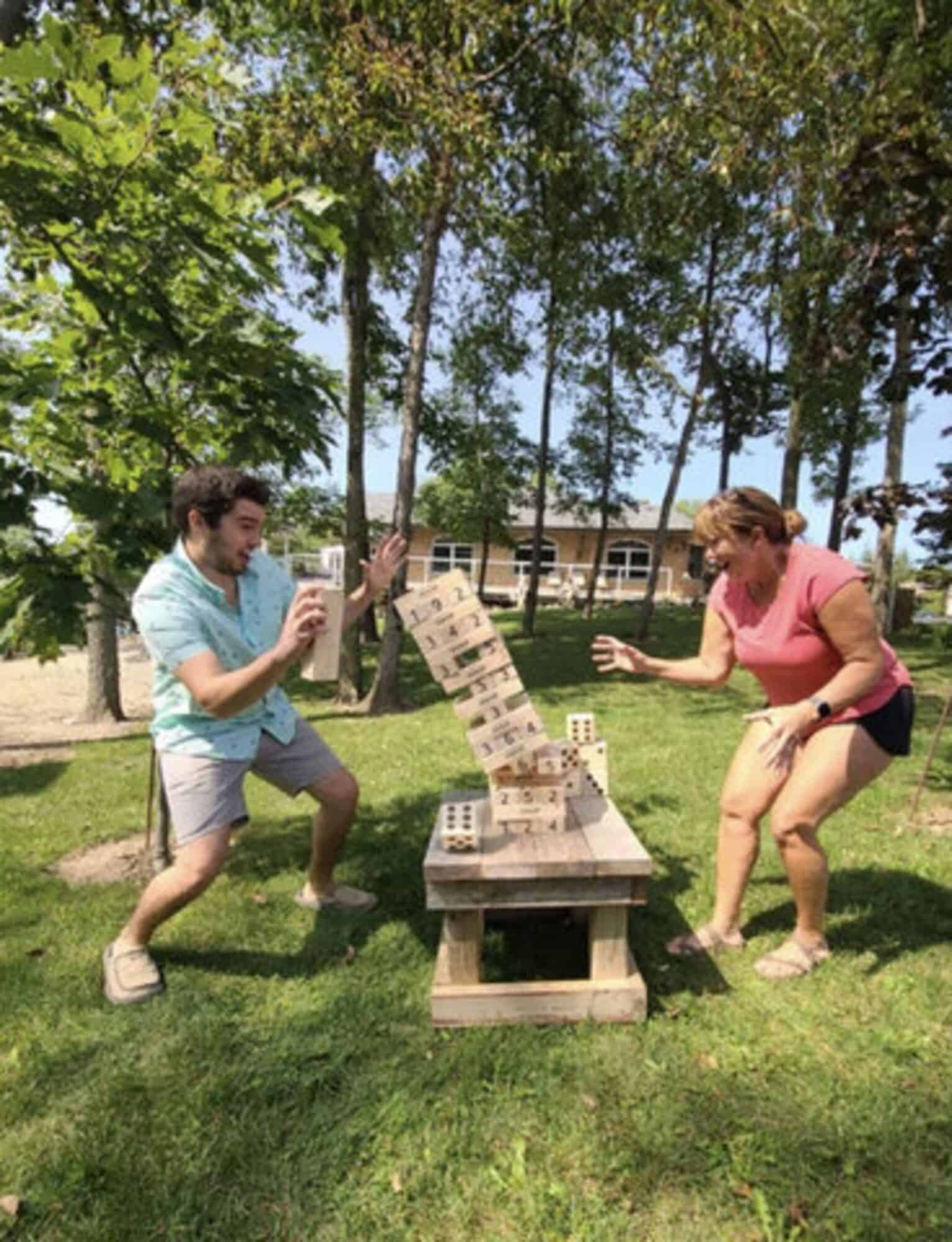 Family Playing Giant Jenga Outdoors Family playing giant Jenga game in park with trees and grass.