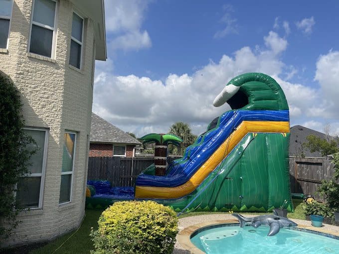 Colorful inflatable water slide with dolphin pool in backyard.
