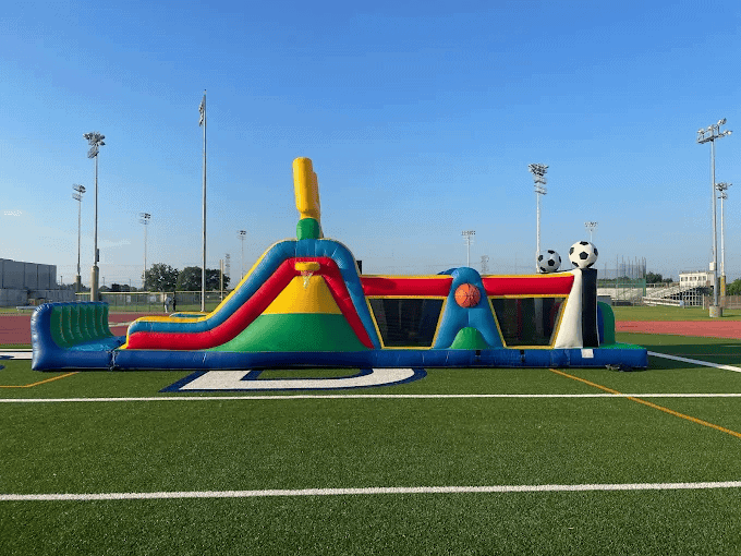 Inflatable Soccer and Obstacle Course Colorful inflatable soccer and obstacle course on sports field for kids' events.